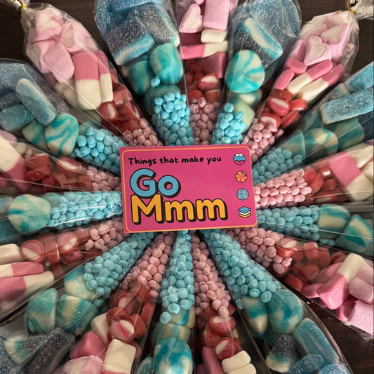 Assorted colorful candies arranged in a circular pattern with a 'Go Mmm' sign in the center.